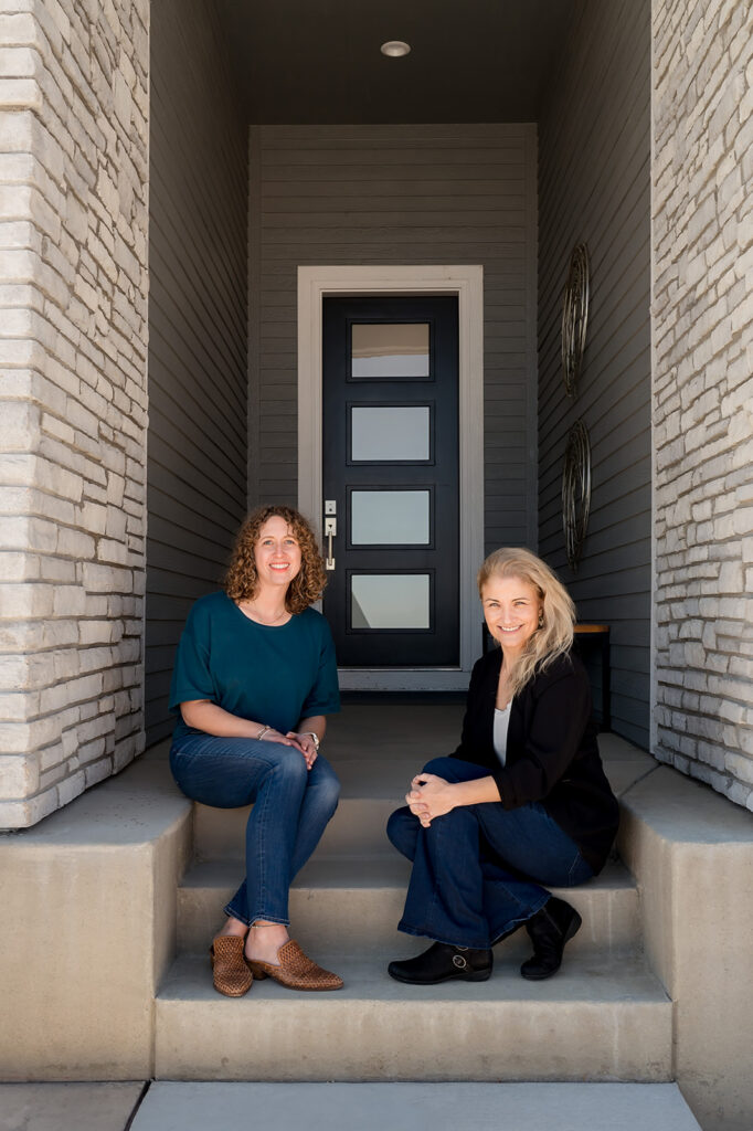 Lauren & Jennifer sitting on front stoop smiling