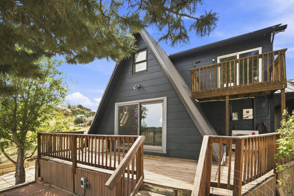Exterior deck and sliding glass door at 4616 Cliff View Lane Fort Collins with upper balcony and ductless heat pump unit installed on exterior wall