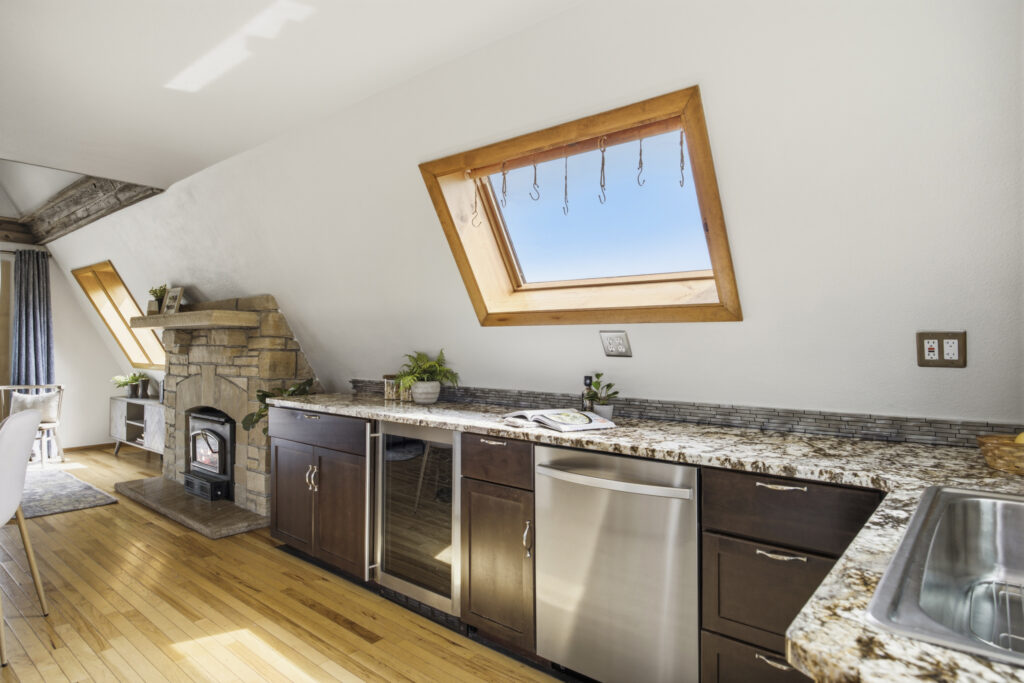 Kitchen at 4616 Cliff View Lane Fort Collins with granite countertops, dark cabinetry, stainless steel dishwasher, and angled skylight window