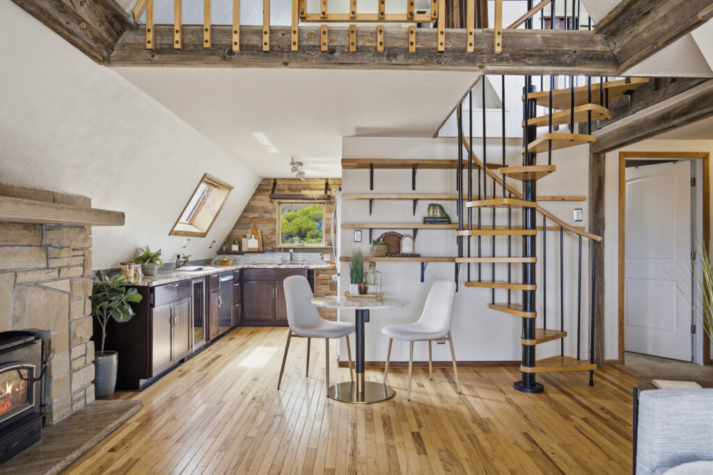 Open main-level floor plan at 4616 Cliff View Lane Fort Collins showing kitchen, dining area, spiral staircase to upper loft, and exposed wood beams